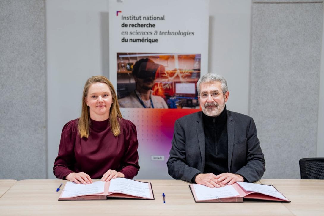 Lillian Røstad and Bruno Sportisse signing the agreement, sitting at a table